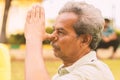 Closeup of of senior man doing alternate Nostril Breathing exercise or nadi shodhana pranayama at park - Concept of healthy active