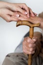 Closeup of senior mans hands and young girl caregiver holding hands on walking stick Royalty Free Stock Photo