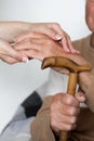 Closeup of senior mans hands and young girl caregiver holding hands on walking stick Royalty Free Stock Photo