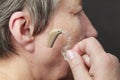 Closeup senior woman using hearing aid