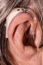 Closeup senior woman using hearing aid