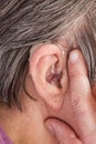 Closeup senior woman using hearing aid