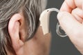 Closeup senior woman using hearing aid