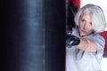 Closeup of serious aged woman boxing punchbag