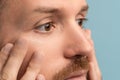 Closeup of serious bearded man looking at wrinkles under eyes touching face skin. Skincare after 40s Royalty Free Stock Photo
