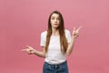 Closeup of serious strict young woman wears white shirt looks stressed and pointing up with finger isolated over pink