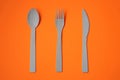 Closeup of a set of spoon, knife, and fork on an orange surface Royalty Free Stock Photo