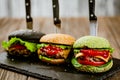 Closeup of set of three color homemade burgers with marble beef with knifes on wooden table. Royalty Free Stock Photo