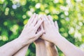 Closeup of several hands touching one another on a blurred green background