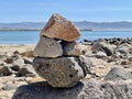 Closeup of several stacked large rocks on the beach with the water in the background and blue sky Royalty Free Stock Photo