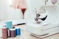 Closeup of sewing machine with fashion designer showroom studio workshop background with new collection of pink pastel female Royalty Free Stock Photo