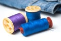Sewing thread spool bobbin on white table on blue jeans background Royalty Free Stock Photo