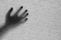 Closeup surface shadow of hand behind gray fabric curtain textured background with copy space in black and white tone in horror co Royalty Free Stock Photo