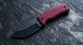 Closeup of a sharp folding knife with a red wooden handle on a dark slate background Royalty Free Stock Photo
