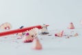 Closeup of a sharpened red pencil with pencil shavings on white surface Royalty Free Stock Photo