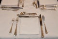 Closeup shiny vintage cutlery, silverware, spoon, fork, knife, white tablecloth and napkins on table Royalty Free Stock Photo