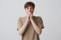 Closeup of shocked amazed young man student with blue eyes and short blond hair covered mouth by hands and looks directly in