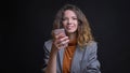 Closeup shoot of young attractive caucasian female messaging on the phone and smiling while looking at camera Royalty Free Stock Photo