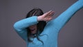 Closeup shoot of young cool brunette female dabbing with confidence looking at camera with background isolated on gray