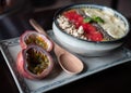 Closeup shot of an acai bowl with fruits and a sliced passionfruit with a wooden spoon