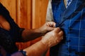 Closeup shot of aged female hands fastening buttons of a suit of his partner