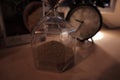 Closeup shot of an alarm clock and a sandglass on the table