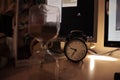 Closeup shot of an alarm clock and a sandglass on the table