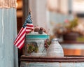 Closeup shot of an American flag in a rusty silver pot with succulents on a porch