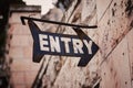 Closeup shot of ancient Entry signage on a rusty metal near a concrete wall