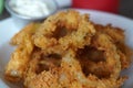 Closeup shot of an appetizing onion ring crisps bowl with a white dipping sauce