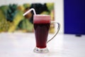 Closeup shot of Arabian juice of Jallab with straw in big glass with blur background