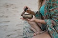 Closeup shot of an Arabic design metallic bowl in beautiful girl's hands in a swimsuit on the beach