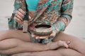 Closeup shot of an Arabic design metallic bowl in beautiful girl's hands in a swimsuit on the beach
