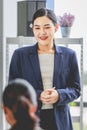 Closeup shot of Asian pretty happy cheerful female businesswoman intern trainee in casual suit standing smiling in company office Royalty Free Stock Photo