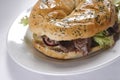 Closeup shot of a bagel of ham and lettuce on white plate Royalty Free Stock Photo