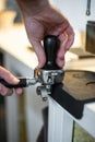 Closeup shot of a bartend holding a coffee tamper and compressing coffee grounds Royalty Free Stock Photo