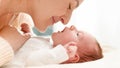 Closeup shot of beautiful young mother cuddling and stroking her little baby son lying on bed in sun light. Concept of Royalty Free Stock Photo