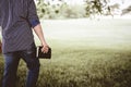 Closeup shot from behind of a male walking on a grassy field while holding the Bible Royalty Free Stock Photo