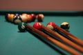 Closeup shot of billiard cues next to the balls on the table