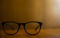 Closeup shot of black eyeglasses on a wooden table on a blurred background Royalty Free Stock Photo