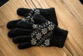 Closeup shot of black knitted gloves lying on wooden table