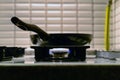 Closeup shot of a black pan on a stove with blue gas flames Royalty Free Stock Photo