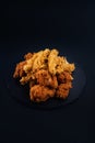 Closeup shot of a black serving plate full of chicken nuggets and crispy fried chicken