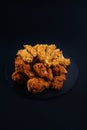 Closeup shot of a black serving plate full of chicken nuggets and crispy fried chicken