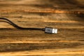 Closeup shot of a black USB cable on a wooden surface Royalty Free Stock Photo