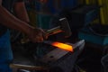Closeup shot of a blacksmith hammering the glowing red hot steel to make a knife Royalty Free Stock Photo