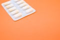 Closeup shot of a blister pack with capsules on an orange background Royalty Free Stock Photo