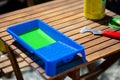Closeup shot of a blue container with green paint on a wooden table with construction tools Royalty Free Stock Photo