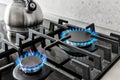 Closeup shot of blue fire from domestic kitchen stove top. Gas cooker with burning flames of propane gas. Silver kettle Royalty Free Stock Photo