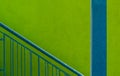 Closeup shot of a blue staircase railing and column in front of a bright green wall Royalty Free Stock Photo